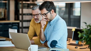 Zwei Mitarbeitende schauen in einen Laptop